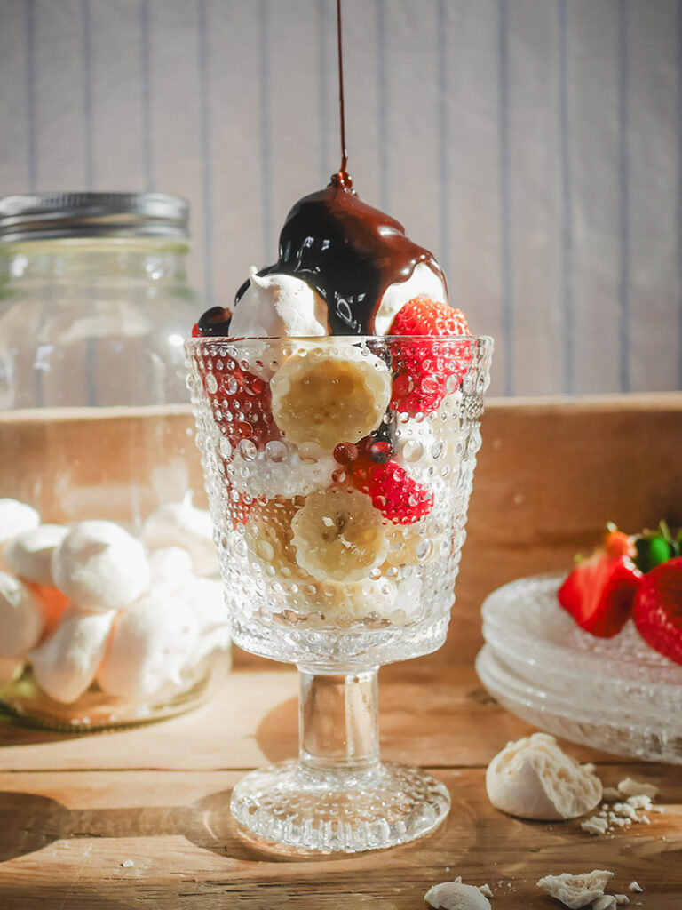 Dessert imGlas mit Baiser, Erdbeeren und Schokoladensauce